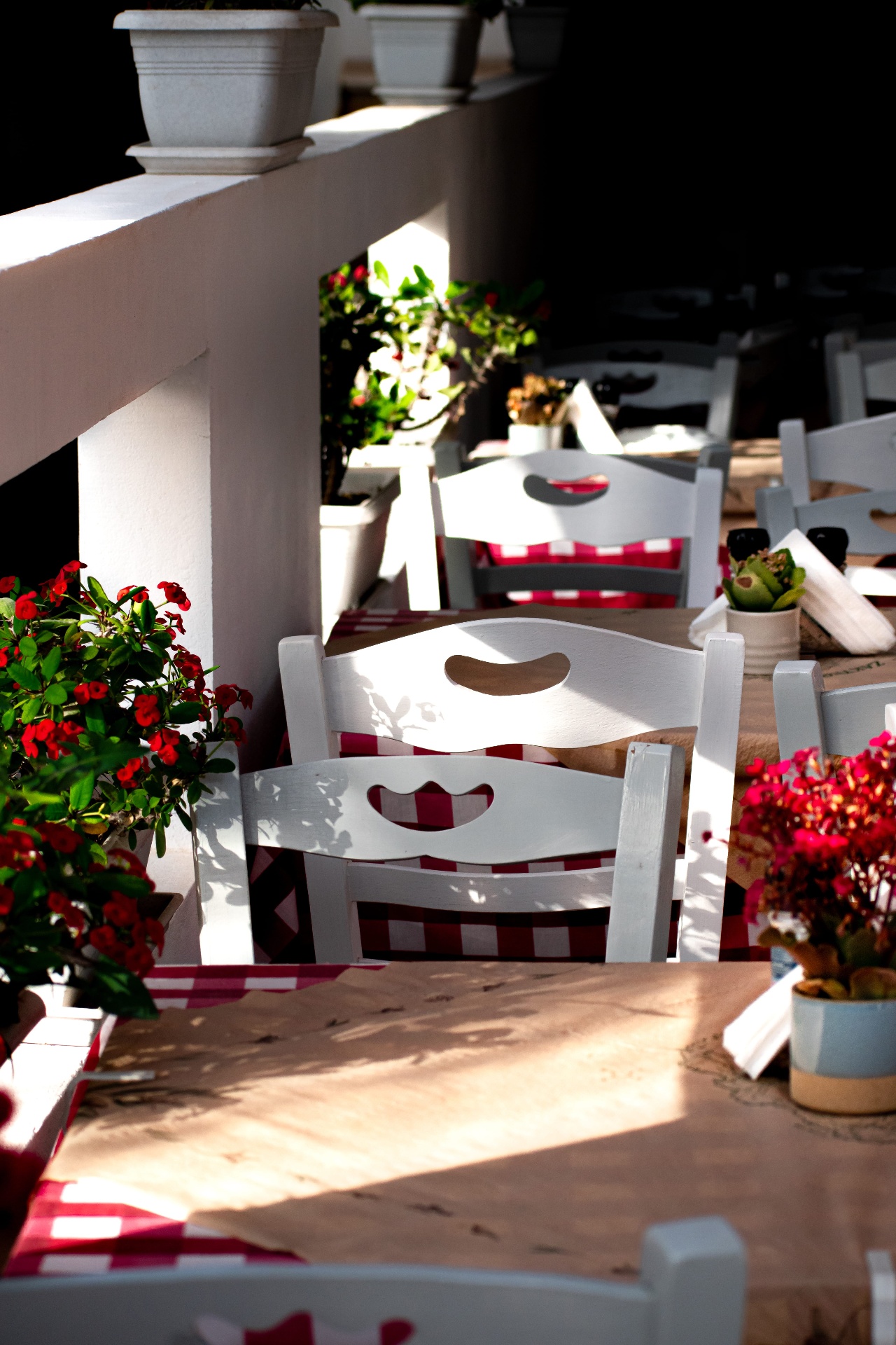 White wooden chairs and red gingham tablecloths
